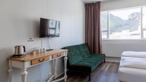 韦斯特曼纳埃亚尔哈马尔旅馆的酒店客房带绿椅和电视