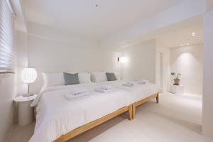 首尔White Linen House的白色的卧室配有一张白色的大床和一盏灯