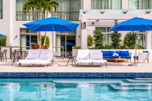 劳德代尔堡Hyatt Centric Las Olas Fort Lauderdale的一座带椅子和遮阳伞的游泳池位于一座建筑旁边