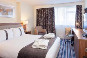 克里克拉格比--北安普敦M1 Jct18假日酒店的配有一张床、一张书桌和一扇窗户的酒店客房