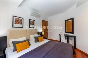 卢斯Baia da Luz Resort的一间卧室配有一张带橙色和灰色枕头的大床