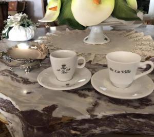 菲乌米奇诺瑞莱别墅酒店的大理石桌子上放两个咖啡杯和酱油