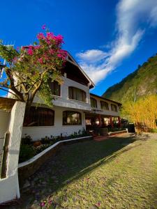 巴尼奥斯Hotel Volcano Baños的一座有树的建筑,上面有粉红色的花朵