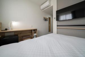 名古屋R&B Hotel Nagoya Shinkansenguchi的卧室配有白色的床和书桌