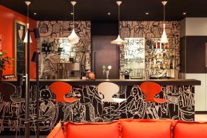 格拉茨宜必思格拉茨酒店的一间酒吧,里面摆放着橙色椅子,墙上挂着涂鸦
