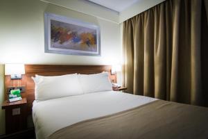切斯特假日切斯特南部酒店的酒店客房设有一张床,墙上挂有绘画作品