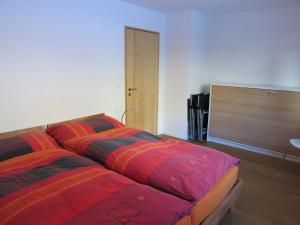 施普吕根Apartment Beeli的一间卧室配有两张带彩色毯子的床
