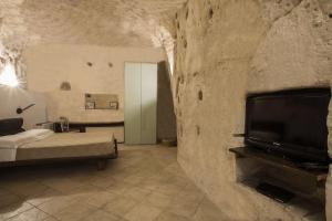 马泰拉圣皮埃特罗巴里萨诺酒店的一间卧室设有一张床,并在石墙内配有电视。