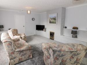 格文Honesty Cottage的客厅配有两把椅子和电视