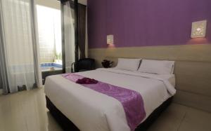 登巴萨巴厘梦幻科斯特尔酒店的一间卧室配有一张大床和紫色墙壁