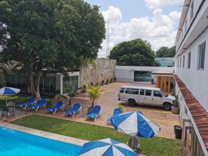 梅里达拉斯达利亚斯酒店的停在游泳池旁的汽车,配有蓝色的椅子和遮阳伞