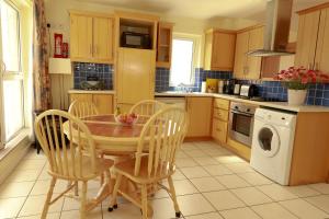 戈尔韦阿拉斯格拉顿公寓的厨房配有木桌、椅子和洗衣机。