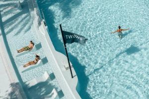 普拉亚登博萨The Ibiza Twiins - 4* Sup的两人在水中悬挂国旗的游泳池游泳