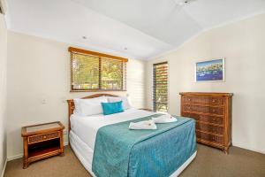 帝坎湾Tin Can Bay Marina Villas的一间卧室配有一张带蓝色毯子的床和梳妆台