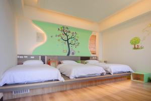 北竿马祖北竿舒漫活海景旅宿 的墙上挂着一幅树壁画的房间里,有两张床