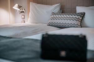 塞萨洛尼基Domotel Olympia的一张带白色床单和枕头的床以及黑色手提箱