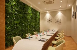 德瓦纳哈利-班加罗尔Click Hotel Bangalore - International Airport的绿墙客房内的一张长桌