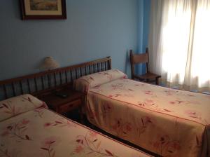 奥利文萨Hostal Los Amigos的一间卧室设有两张床、一张桌子和一个窗口