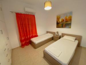 法罗斯岛Sifneiko Arxontiko的一间设有两张床和红色窗帘的房间