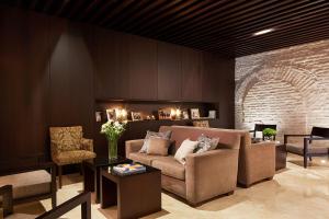 塞维利亚卢赛罗波萨达酒店的带沙发和椅子的客厅以及砖墙