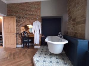 莫珀斯Castle View Bed and Breakfast的一间带白色浴缸和砖墙的浴室