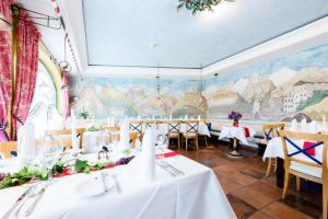 兰德埃克斯科洛芬斯坦酒店的一间设有白色桌子和壁画的用餐室