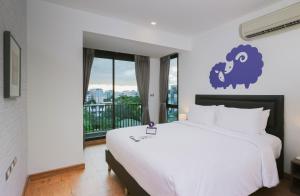 曼谷Kokotel Bangkok Sukhumvit 50 - SHA Extra Plus的一间带大床的卧室和一个阳台