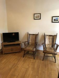 斯皮德尔Spiddal Cottage的客厅配有两把椅子和电视