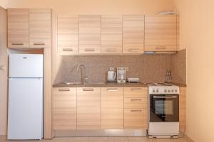 波罗斯Akrogiali Studios的厨房配有木制橱柜和白色冰箱。