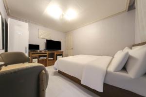 春川古德斯代格兰德春川汽车旅馆的一间卧室配有一张床和一张书桌及电视
