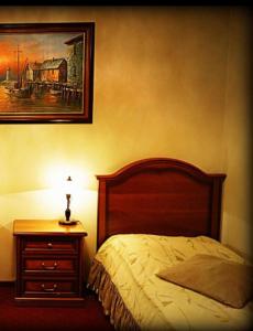 奥普尔扎德泽酒店的一间卧室配有一张床和一个挂着照片的床头柜