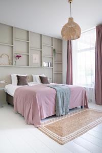 莱茵河畔阿尔芬Boutique Hotel - de Stadsherberg Alphen的一间卧室配有一张带粉色毯子的大床