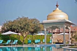 斋浦尔Tree of Life Resort & Spa Jaipur的凉亭,毗邻带椅子和遮阳伞的游泳池