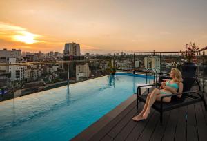 河内Soleil Boutique Hotel Hanoi的坐在游泳池旁椅子上的女人