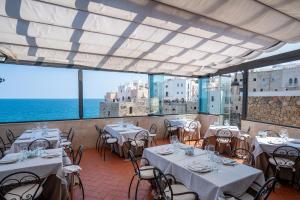 滨海波利尼亚诺萨拉森尼科沃酒店的一间设有白色桌椅的海洋餐厅