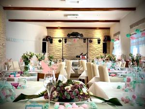 Krupka栗子下酒店及餐厅的宴会厅配有白色的桌椅和鲜花
