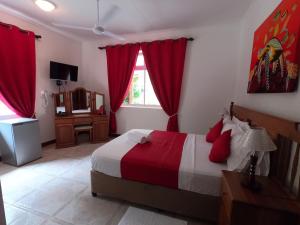 昂斯拉齐奥莱富安湾旅馆的一间卧室配有一张带红色窗帘的床和一扇窗户