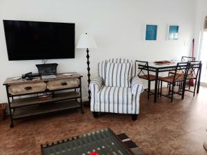 帕诺滩Sunrise Ocean Suites的客厅配有电视、椅子和桌子