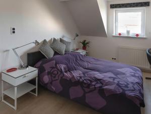布鲁塞尔Modern duplex with garden的一间卧室配有紫色的床和一张带台灯的桌子