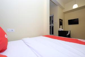 金马仑高原OYO 44029 Tudor Home Inn的卧室配有红色和白色的床和椅子