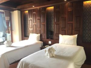 皮皮岛吉吉住所酒店的一间设有两张带白色床单和弓形床的房间