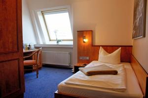 布伦瑞克德意志豪斯酒店的一间卧室配有一张带书桌的床和窗户。
