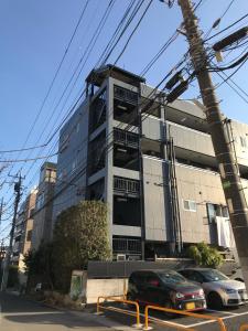 松户市松戸 テイクファイブ - 水色1DK Nomad松戸宿015的前面有汽车停放的建筑