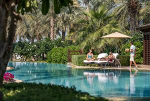 迪拜朱美拉海滩迪拜四季酒店的一群人坐在游泳池周围