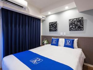 那霸Living Inn Asahibashiekimae Premier的一间卧室配有一张带蓝色和白色枕头的床