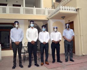 斋浦尔Dera Rawatsar - Heritage Hotel的一群戴面具的人站在一座建筑物前