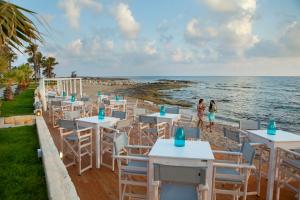 帕福斯爱美尔海滩酒店及度假中心的海滩上的餐厅,配有桌椅