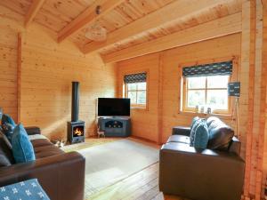 斯利福德Tythe Lodge的客厅配有两张沙发和一个炉灶