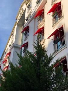 阿达纳Riva Reşatbey Luxury Hotel的一座建筑,前方有红阳台和一棵树