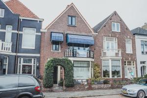 海边的艾格蒙特B&B de Zandtaart的一座红砖房子,前面有凉亭和汽车